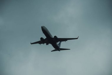 Gri gökyüzü düzlemde silüeti. Yolcu uçağı yüksek gökyüzü, uçuş uçar. Uluslararası uçuşlar, teslim, ulaştırma. Uçuş ve hava koşulları kavramı.