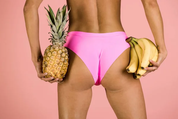 Sexy nádegas de menina em biquíni com banana e abacaxi — Fotografia de Stock