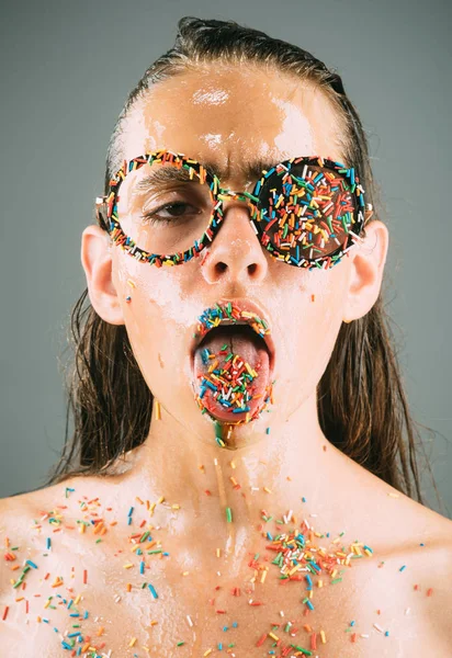 Sprinkles lipstick and glasses on girl, valentines day. Beauty and fashion model of glamour girl. Diet and sweet dessert, easter. Makeup of sugar candy kiss on lips. Young woman with sprinkles makeup.