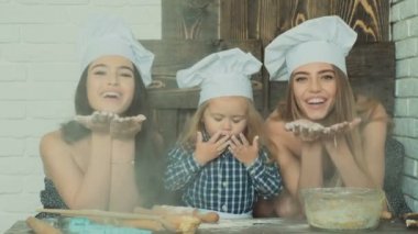 Mutlu aile birlikte fırın hazırlıyor. Anne ve kız çocuk kurabiye pişiriyor ve mutfakta eğleniyorlar. Ev yapımı yemek ve küçük bir yardımcı..