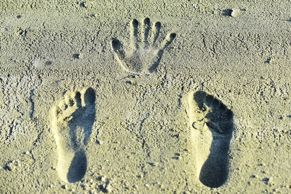 Handprint and footprints on sand