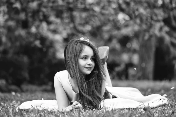 Petite fille sur herbe verte avec des pétales — Photo