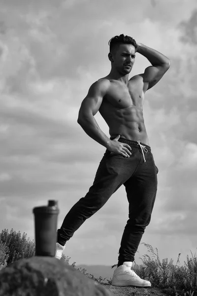 Uomo muscoloso posa vicino bottiglia d'acqua — Foto Stock