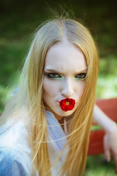 Mujer de belleza con flor roja en la boca. Modelo de belleza con pelo largo y rubio, peinado . — Foto de Stock