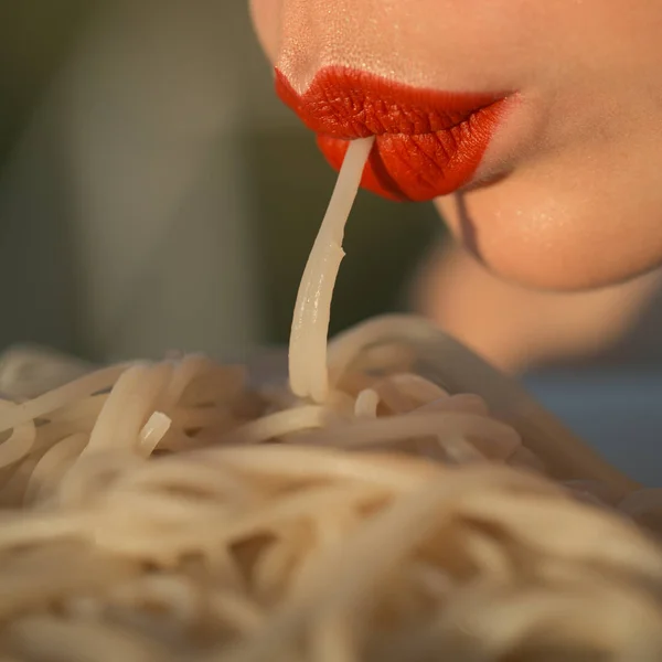 Maquillaje labios comer pasta o espaguetis al aire libre, primer plano. maquillaje o moda, labios sexy con lipstock rojo de mujer o niña comiendo espaguetis — Foto de Stock