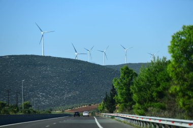 Yel değirmenleri, Rüzgar jeneratörleri Hill'de, dağ. Peyzaj dağlar, yollar, yollar, arabalar. Alternatif enerji kaynakları kavramı. Dağlar üzerinde dev beyaz yel değirmenleri.