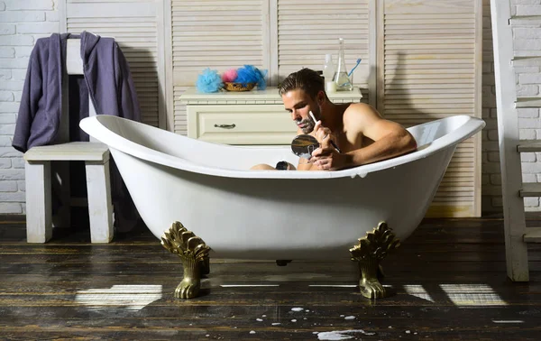 Barbear homem com navalha, sabão, espelho na banheira, banheiro — Fotografia de Stock