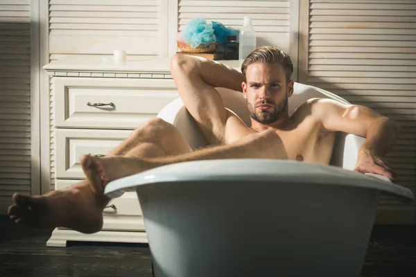 Bonito jovem na banheira em casa tomando banho — Fotografia de Stock