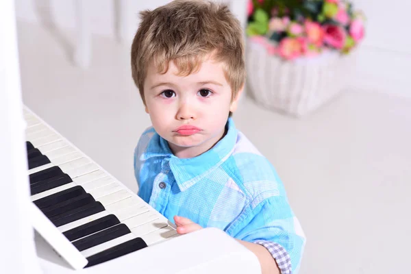 어린이 피아노 키보드, 흰색 배경에 가까이 앉아. 귀 엽 고 사랑 스러운 소년 피아노의 키보드에 손가락을 넣습니다. 아이가 악기 근처 레저 지출. 어린 시절 엘리트 개념. — 스톡 사진
