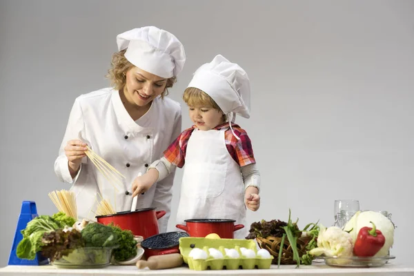 Máma a dítě se usmívající se tvář společné vaření špaget. — Stock fotografie