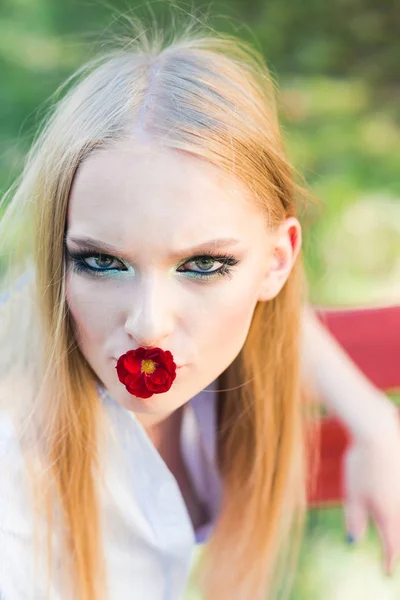 Móda žena s blond dlouhé vlasy, účes s červenou květinou v ústech. Móda dívka s glamour looku, make-up, vlasy. — Stock fotografie