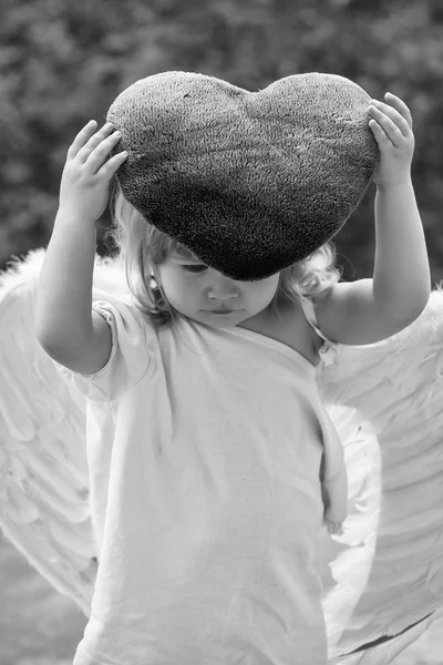Μικρό αγόρι σε φτερά αγγέλου και καρδιάς μαξιλάρι — Φωτογραφία Αρχείου
