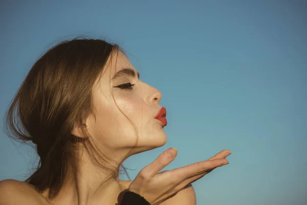Vacker kvinna modell poserar och blås kiss på blå himmel bakgrund, kopia utrymme — Stockfoto