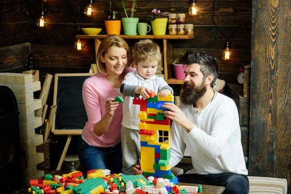 Edukacyjne koncepcji gry. Rodziny na zajęty twarz spędzić razem czas w pokoju zabaw. Dziecko z rodzicami grać z plastikowych klocków, budować budowlanych. Ojciec, matka i syn ładny grać z cegły Konstruktor. — Zdjęcie stockowe