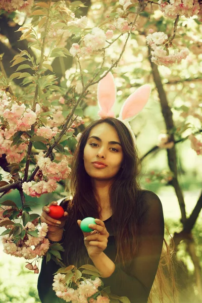 Meisje met bunny oren glimlachend met gekleurde eieren, sakura — Stockfoto