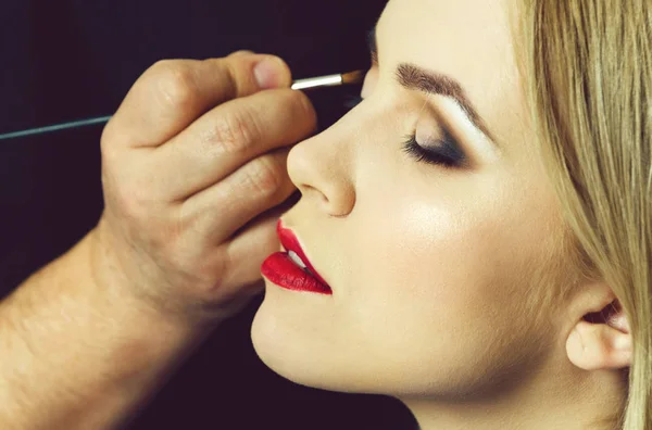 Mulher com olhos fechados e lábios vermelhos recebendo maquiagem — Fotografia de Stock