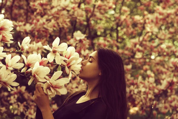 Bedårande flicka lukta rosa, blommande, magnolia blommor från t — Stockfoto