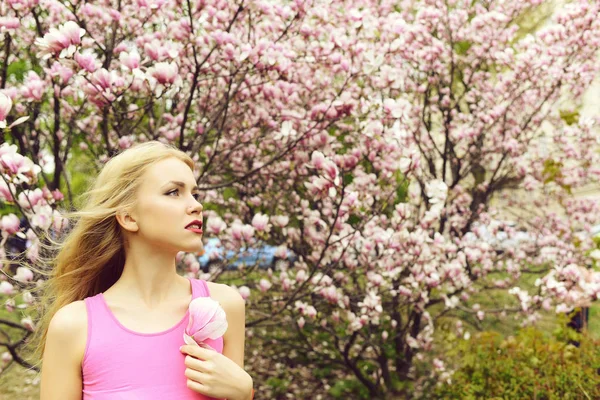 Mooi meisje houdt magnolia bloem bloeiende boom, voorjaar gard — Stockfoto