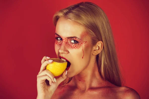 Jong meisje bijten gele citroen op rode achtergrond — Stockfoto