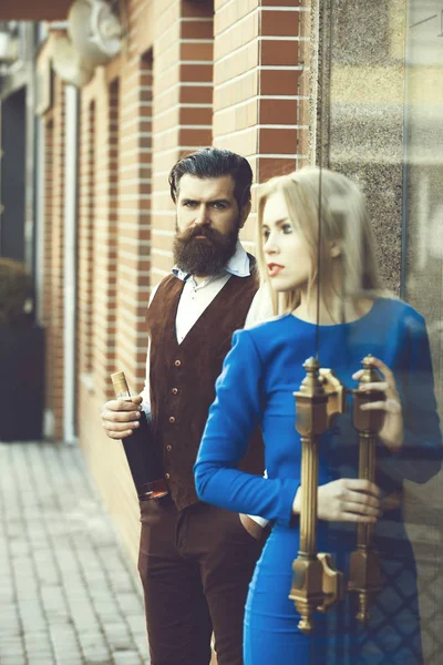 Man holding bottle of wine with woman opening glass door — Stock Photo, Image