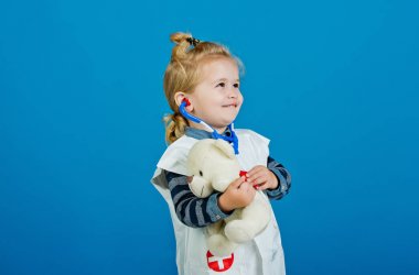 Doktor üniforma içinde mutlu çocuk stetoskop ile oyuncak hayvan incelemek