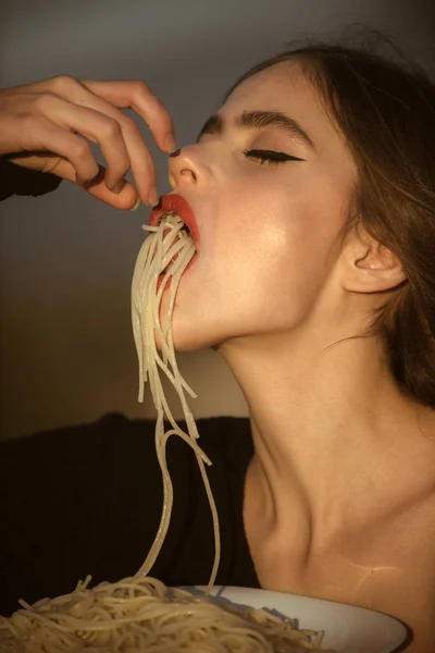 鑑定やレストランの評論家としてパスタを食べる女。ダイエットと健康的な有機食品、イタリア。飢餓、食欲、レシピ。赤い唇の女性シェフがパスタを食べる。イタリア マカロニやスパゲティ、夕食に調理. — ストック写真