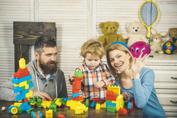 Los padres y el niño con caras felices hacen construcciones de ladrillo . — Foto de Stock