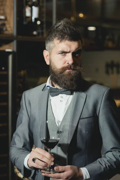 Selbstbewusster Winzer in romantischer Atmosphäre eines Zigarrenclubs. Zigarrenclub, seriöser Winzer mit Glas im Business-Anzug. — Stockfoto