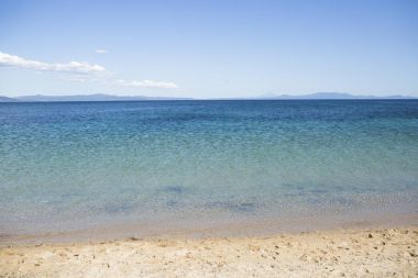 Deniz yüzeyi dalgalar, kum plaj ve dağlar manzarası ile parlayan görüntüleyin. Doğal güzellik, parlayan, parıldayan, şeffaf temiz deniz suyu. Cennet kavramı. Geri kalanı için yer ve sakin ol, çare.