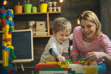 Anne ve mutlu oğul Oluşturucu ile oynamak. Annelik kavramı. Çocuk oyuncakları ve kara tahta arka plan ile. Oluşturucu ile evde oynarken aile. Anne ve çocuk oyuncak arabalar, tuğla ile oynamak.