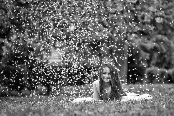 Yaprakları yeşil çimenlerin üzerinde küçük kız