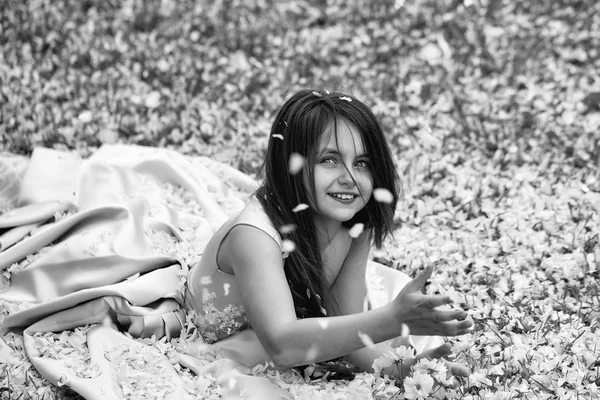 꽃잎과 푸른 잔디에 어린 소녀 — 스톡 사진