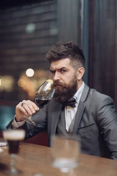 Junger Mann hält ein Glas mit Rotwein in der Hand, Bar im Hintergrund — Stockfoto
