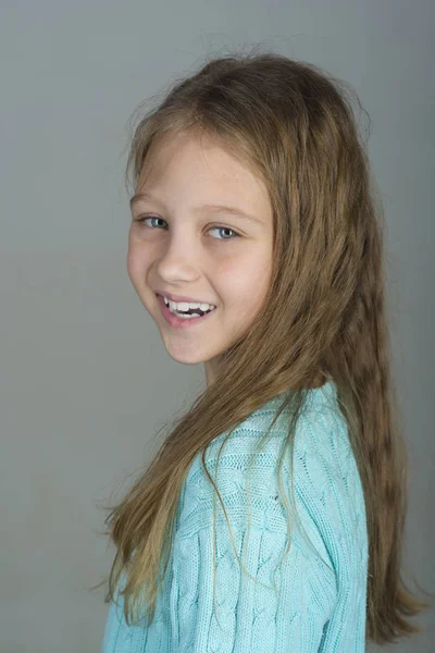 Pequeña chica linda con estilo. Está vestida de azul. Sobre el fondo de color gris —  Fotos de Stock