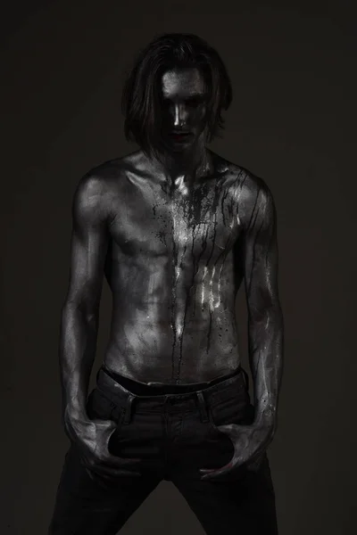 Hombre con torso desnudo cubierto con pintura plateada, fondo oscuro . — Foto de Stock