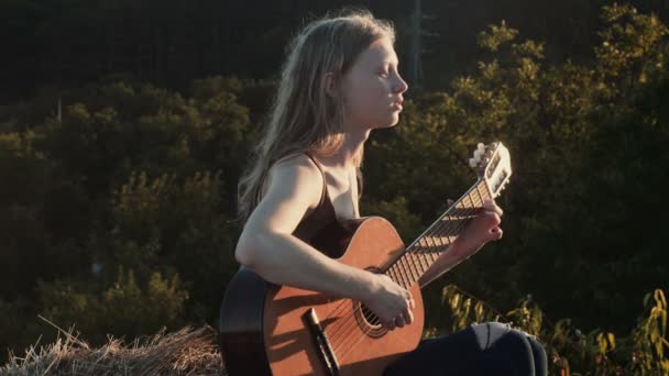 ギターを弾いている女の子 フラグメント 夕日にギターを弾く女性 — ストック動画