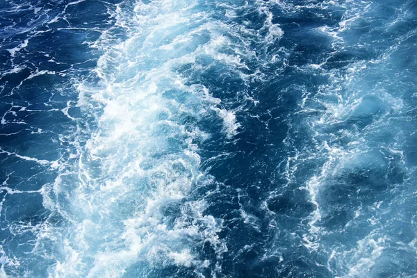 Espuma blanca de olas sobre agua azul del océano. Textura de la superficie del mar con olas. Hermoso fondo, brillante, brillante. Mar, textura del agua del océano. Concepto de fondo . — Foto de Stock