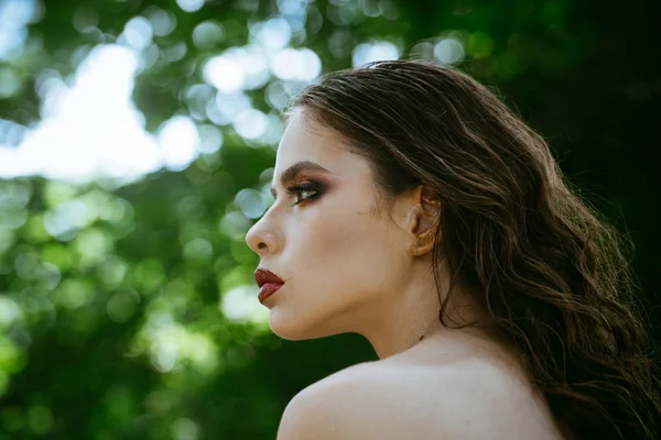 Chica con cara de maquillaje, belleza. Mujer con el pelo largo morena en la naturaleza. Mujer con peinado rizado y hombro desnudo en el día de verano. Modelo de moda con look glamuroso. Cuidado del cabello, terapia y tratamiento —  Fotos de Stock