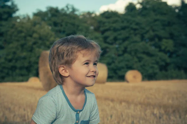 Маленький ребенок улыбается на поле с тюками сена, сельское хозяйство — стоковое фото