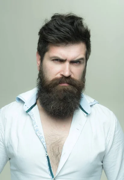 Man with long beard, mustache and stylish hair, light background. Macho on strict face, wears unbuttoned shirt. Guy with modern hairstyle visited hairdresser. Barbershop or hairdresser concept. — Stock Photo, Image