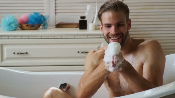 若いハンサムな男は浴槽でリラックスします Buthtub で風呂に入ってひげを持つ男 男性は 幸福とリラックスで高級バスタブで泡泡風呂で覆われています — ストック動画