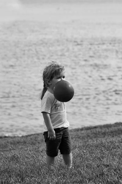 Schattige babyjongen speelt met oranje speelgoed ballon — Stockfoto