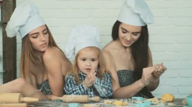 Lezbiyen çift ile onların evlat edinilmiş çocuk yemek. Kız onların kardeşi ile pişirme.