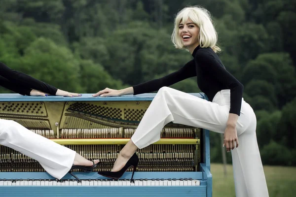 Kvinnor spela grand piano med ben i fashionabla skor utomhus. — Stockfoto