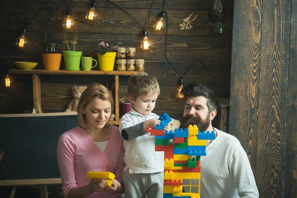 教育游戏的概念 家庭在繁忙的面孔一起花费时间在娱乐室 母亲和可爱的儿子玩构造砖 孩子与父母玩塑料积木 建造建筑 — 图库照片