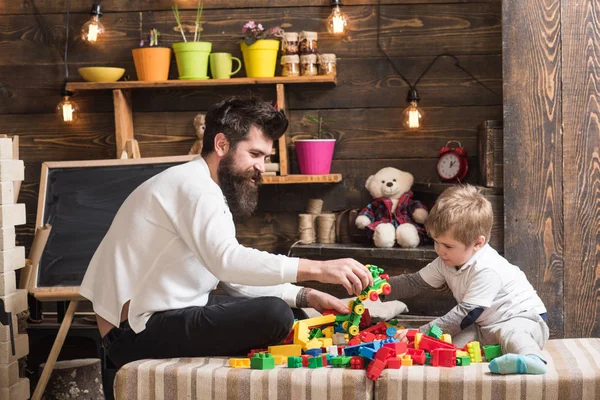 父亲和快乐的儿子玩构造器 父亲的概念 背景上有玩具和黑板的托儿所 家庭在家里玩构造函数 爸爸和孩子玩玩具车 — 图库照片