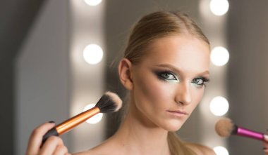 Kadın kullanın fırçalar makyaj için sima. Genç yüz cilt güzellik salonda kadınla.