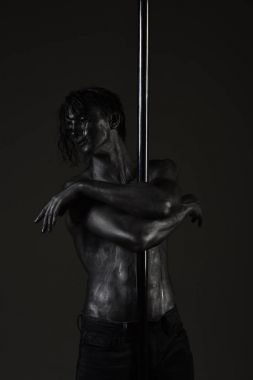 Genç güçlü kutup dans adam koyu arka plan üzerinde.