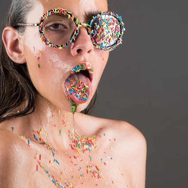 Mujer joven con maquillaje de aspersión. mujer en gafas de moda con salpicaduras en la lengua y los labios —  Fotos de Stock