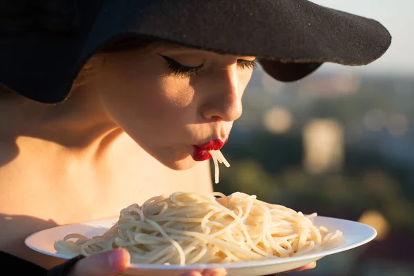 Restaurante crítico macarrão italiano tatuado. restaurante, mulher com lábios vermelhos em chapéu preto comer macarrão . — Fotografia de Stock